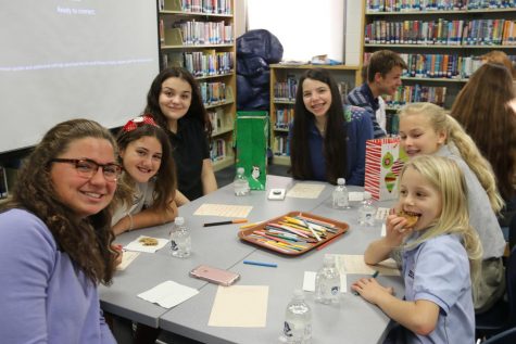 HAPPY TO HELP: Gabriella Donahue ’20 (left) and Sophia Monticciolo ’20 (center) pause for a photo with new friends from Middle and Lower Division, as one very excited Lower Division student enjoys a snack.