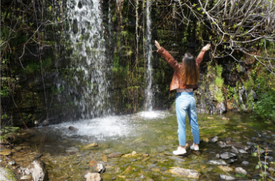 CELEBRATING FAMILY ROOTS: Akers poses with a beautiful waterfall in Patones, Spain, where all the houses are made of slate rock.